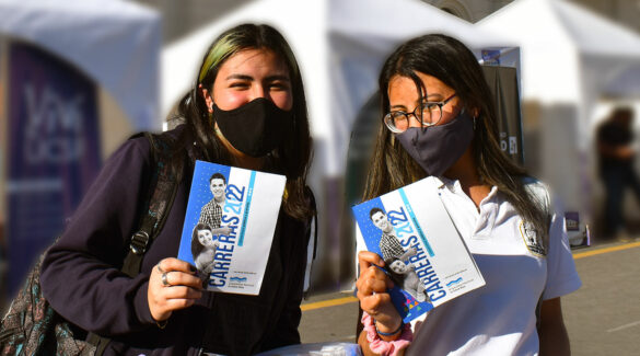 Estudiantes sonrientes con barbijo con folleto de la UNER en la mano.