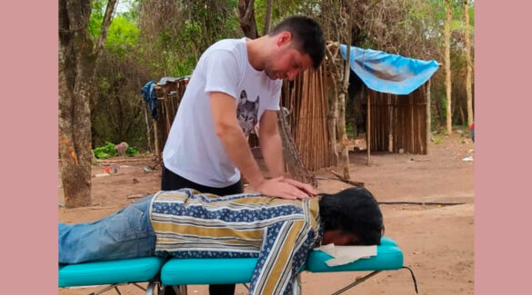 Un estudiante de Kinesiología atiende un paciente sobre una camilla.