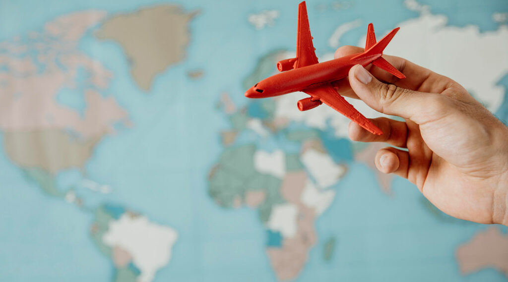 Vista lateral de la persona que sostiene una figurilla de avión sobre el mapa