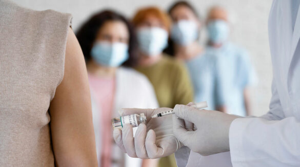Personas con barbijo haciendo fila para aplicarse una vacuna.