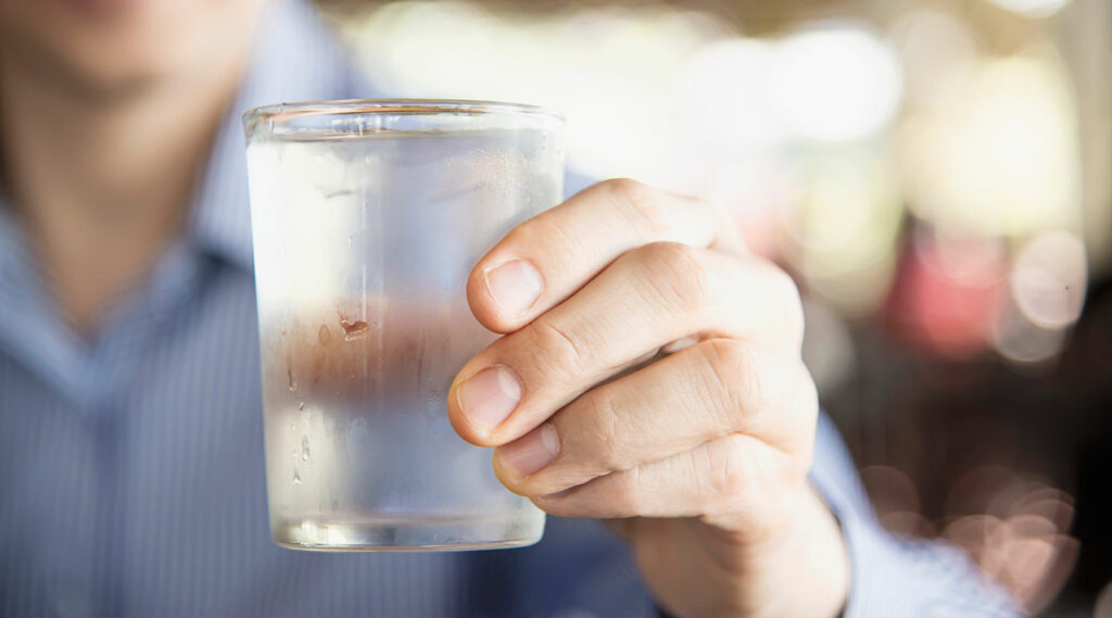mano sosteniendo un vaso de agua fresca