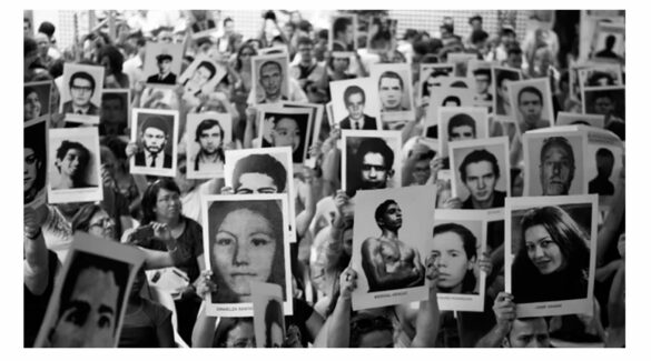 Personas sosteniendo fotos de desaparecidos en la última dictadura militar argentina.