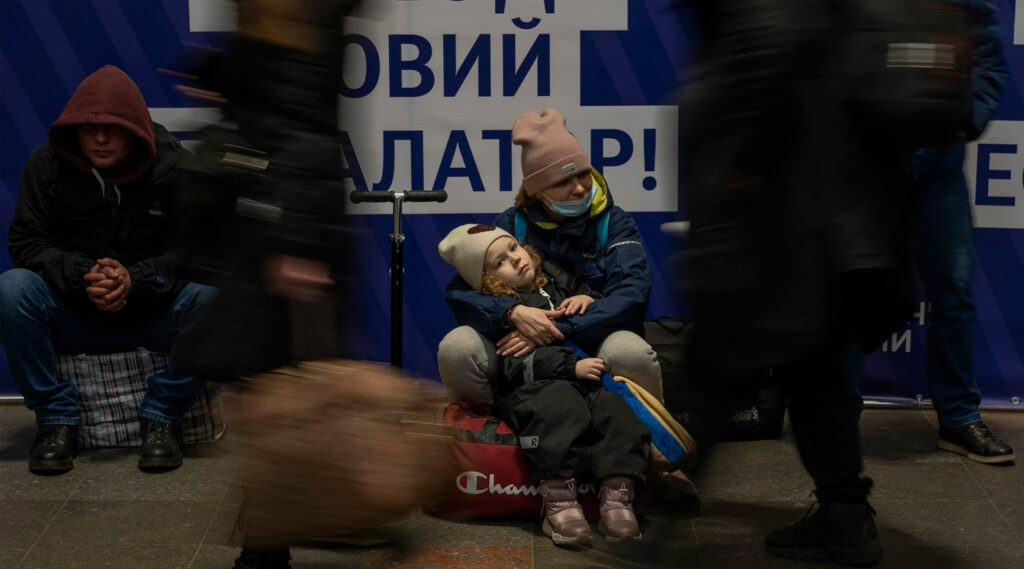 Una mujer con su hija espera un tren mientras intentan salir de la estación de tren de Kiev, Ucrania.