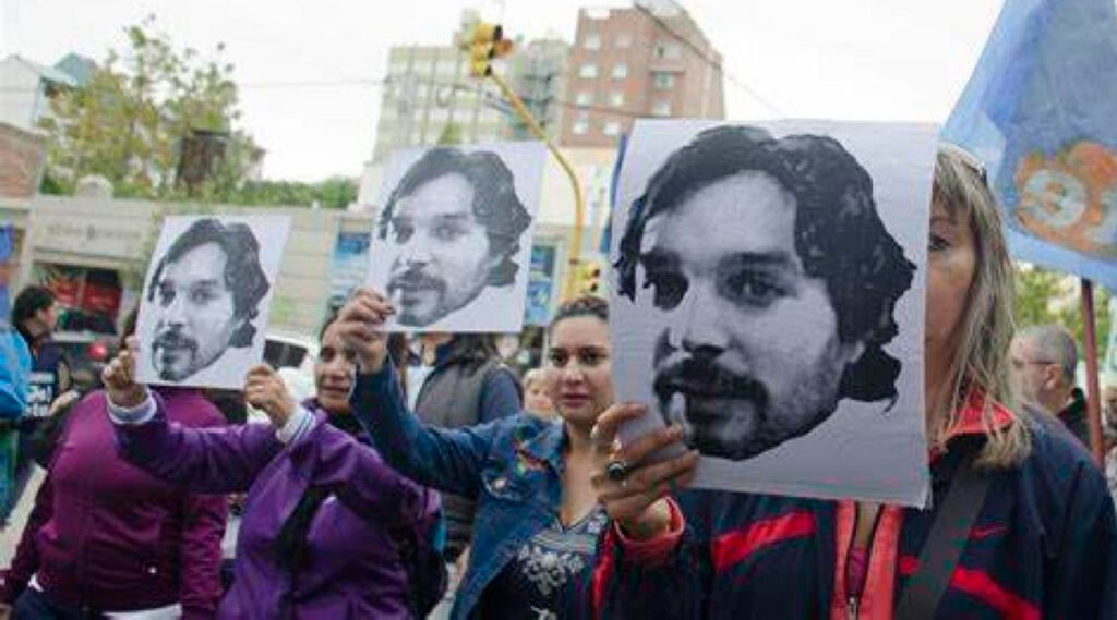personas sosteniendo pancartas con la cara del docente asesinado en 2007, a 15 años del hecho.