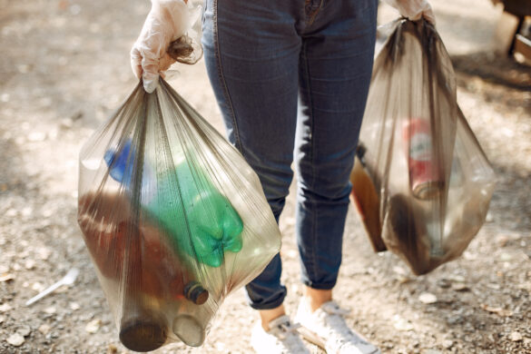 mujer cargando bolsas con botellas de plástico y latas