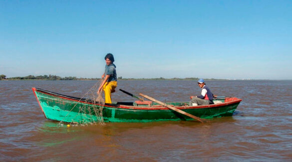 Dos pescadores sobre una canoa en medio del río.
