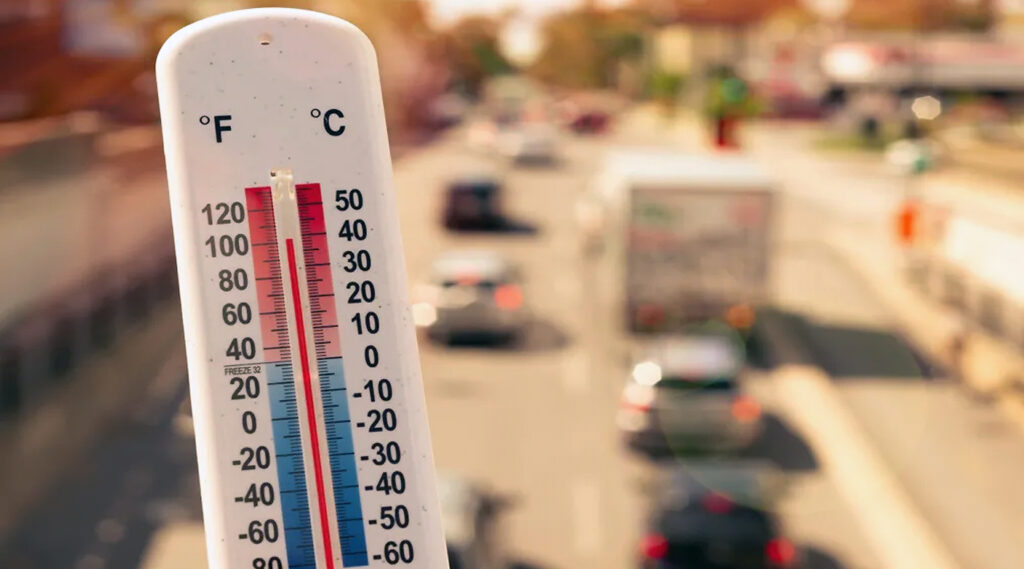 Un termómetro sobre un fondo urbano de coches circulando en desenfoque