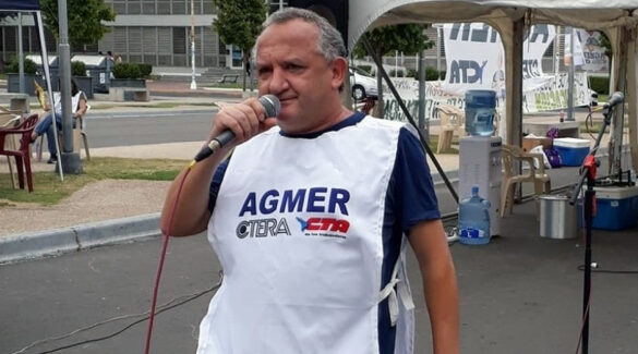 Guillermo Sampedri sosteniendo un micrófono al aire libre, de día; en lo que parece ser una feria o campamento