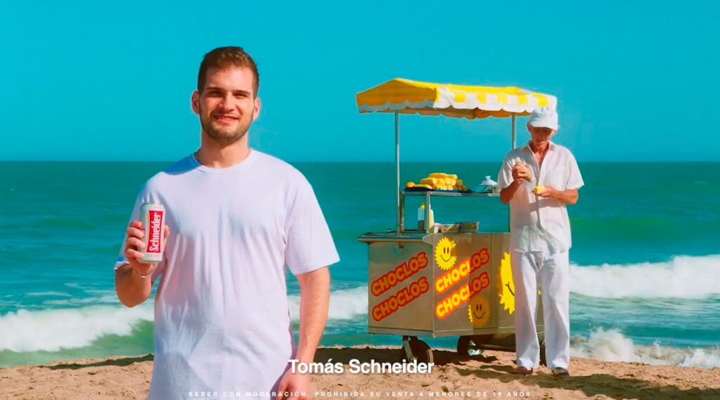 Tomás Schneider en una playa con una lata de cerveza en la mano.