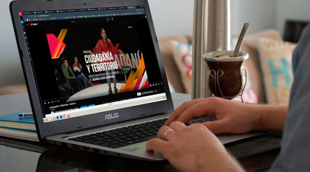 Estudiante viendo un video del ciclo Ciudadanía y Territorio en una notebook. De fondo se ve un mate.