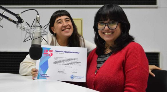 Clara Chauvín y Andrea Sosa Alfonzo, conductoras del podcast Juntas, posan sonrientes en el estudio de Radio Uner Concepción del Uruguay, junto al diploma recibido.
