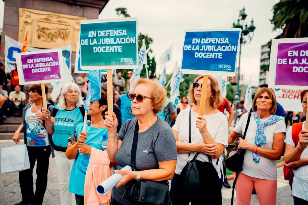 Docentes marchando con pancartas que rezan "en defensa de la jubilación docente".