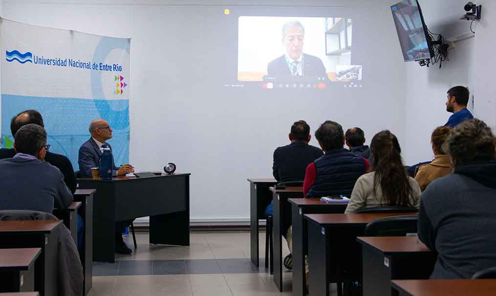 El Rector Andrés Sabella moderando la segunda charla en el marco de los 52 años de la UNER, junto a personal de la universidad que presenció la actividad virtual desde el aula híbrida del Rectorado.