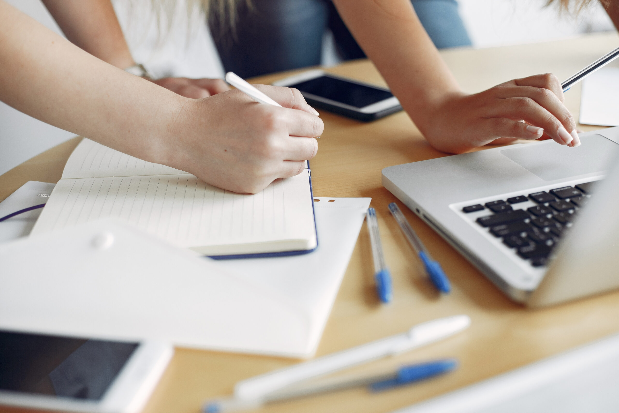 Dos chicas con remeras blancas trabajando sobre un escritorio