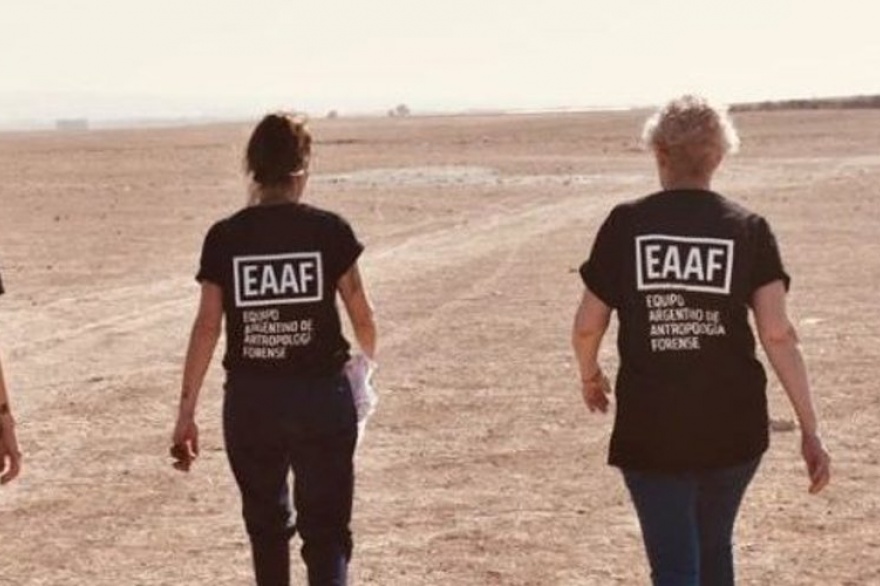 Dos personas del Equipo argentino de antropologia forense de espalda caminando en una playa