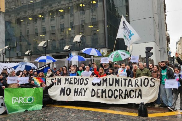 Personas en una manifestación llevando una bandera que dice "sin medios comunitarios no hay democracia"