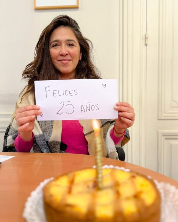 Victoria Montenegro sosteniendo un cartel que dice "felices 25 años"