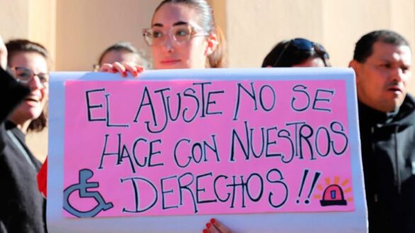 Una chica sosteniendo un cartel hecho a mano con la leyenda "el ajuste no se hace con nuestros derechos"
