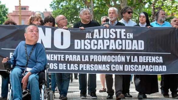 personas sosteniendo una bandera "no al ajuste de discapacidad"