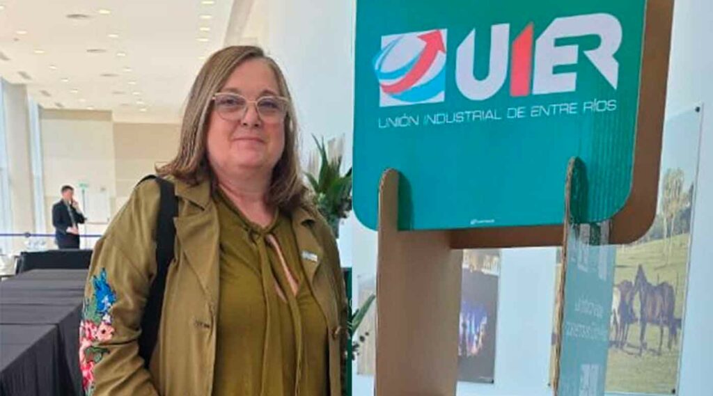 La vicerrectora de UNER, Gabriela Andretich, posando junto a un cartel de la UIER en el Centro Provincial de Convenciones de Paraná.