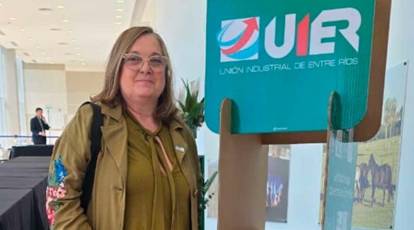 La vicerrectora de UNER, Gabriela Andretich, posando junto a un cartel de la UIER en el Centro Provincial de Convenciones de Paraná.