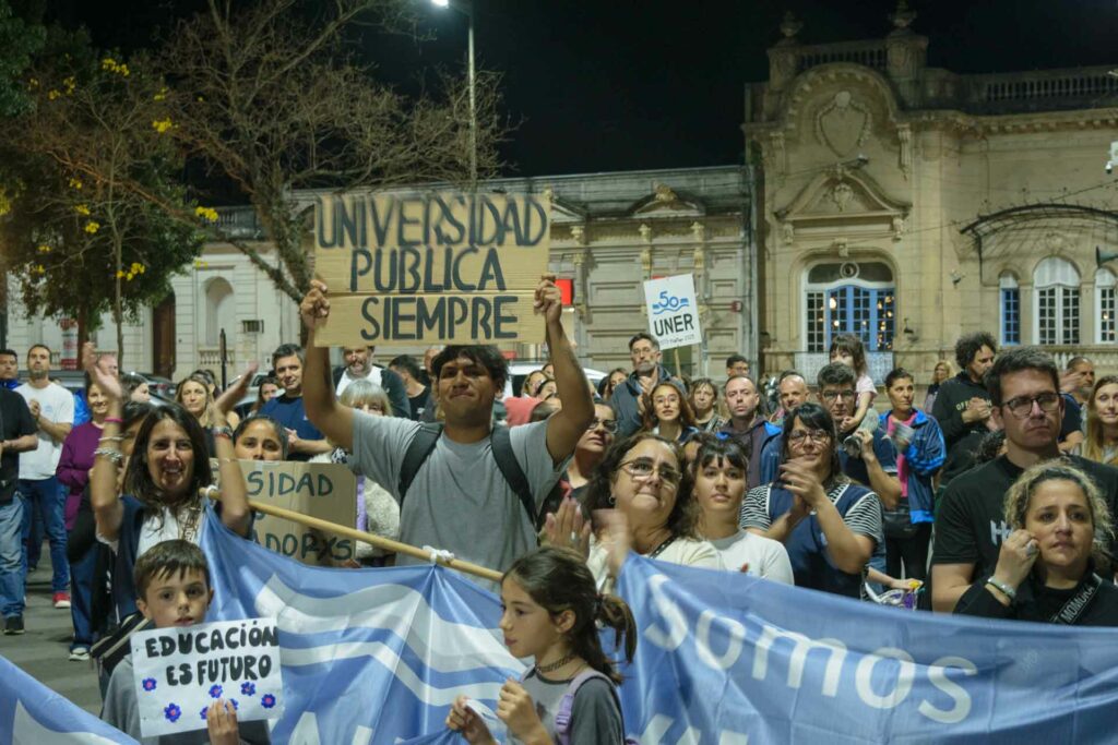 Personas durante la marcha en defensa de la universidad pública en Concepción del Uruguay, sosteniendo carteles y banderas alusivas.
