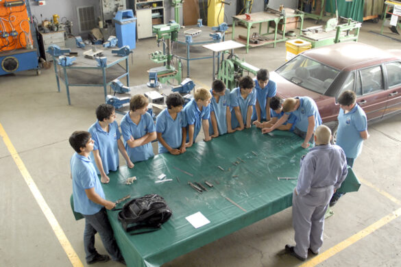 Toma desde arriba de una mesa de trabajo con estudiantes de escuela técnica y su profesor.